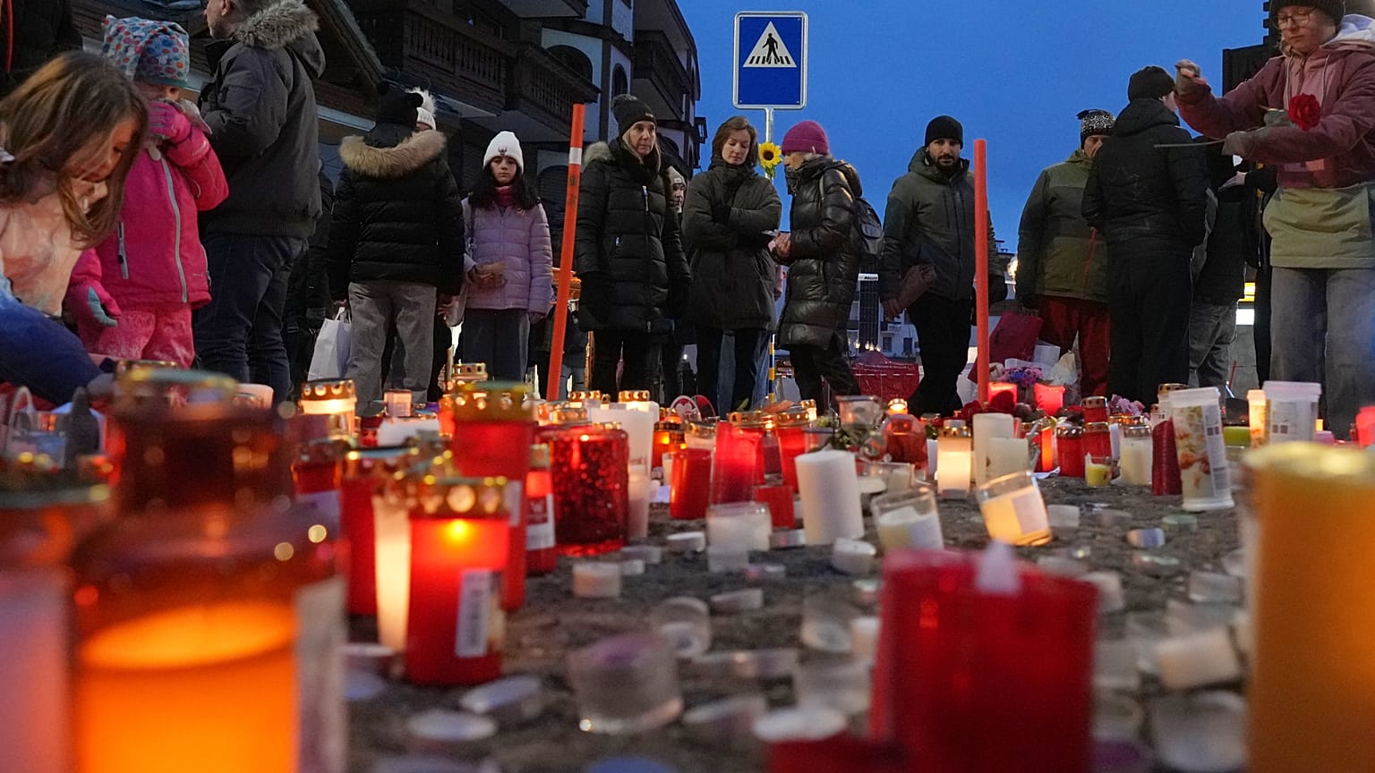 People light candles near the sealed off Le Constellation bar in Crans-Montana, Swiss Alps, Switzerland, Friday, Jan. 2, 2026.