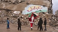 اجرای دلقک ۳۸ ساله فلسطینی در لباس بابا نوئل برای کودکان غزه در ۲۹ دسامبر ۲۰۲۵، در حالی که پس‌زمینه به زبان عربی نوشته شده است که «فردا بهتر خواهد بود» 