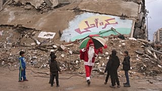 اجرای دلقک ۳۸ ساله فلسطینی در لباس بابا نوئل برای کودکان غزه در ۲۹ دسامبر ۲۰۲۵، در حالی که پس‌زمینه به زبان عربی نوشته شده است که «فردا بهتر خواهد بود» 