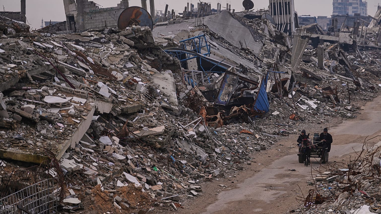 فلسطينيون يسيرون في شارع تحيط به مبانٍ مدمّرة جرّاء العمليات الجوية والبرية الإسرائيلية في حي الشيخ رضوان بمدينة غزة، الثلاثاء 30 ديسمبر/كانون الأول 2025.