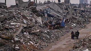 فلسطينيون يسيرون في شارع تحيط به مبانٍ مدمّرة جرّاء العمليات الجوية والبرية الإسرائيلية في حي الشيخ رضوان بمدينة غزة، الثلاثاء 30 ديسمبر/كانون الأول 2025.