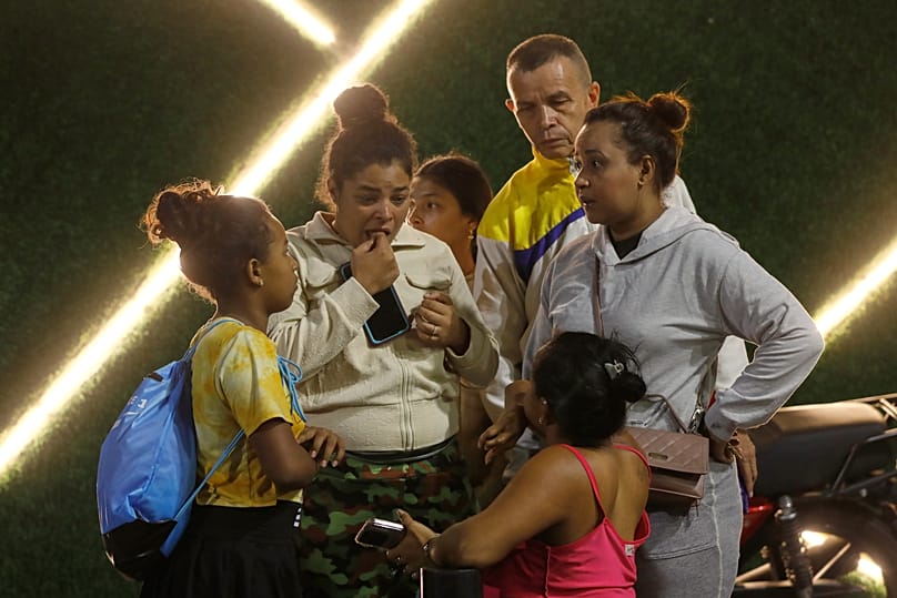 Residents evacuate a building near the Miraflores presidential palace after explosions and low-flying aircraft were heard in Caracas, Venezuela, Saturday, Jan. 3, 2026.