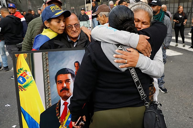 Partidarios del presidente venezolano Nicolás Maduro se abrazan en el centro de Caracas, Venezuela, el sábado 3 de enero de 2026.