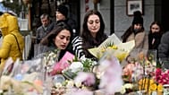 Two women lay flowers near the sealed off Le Constellation bar in Crans-Montana, Swiss Alps, Switzerland, Friday, Jan. 2, 2026.