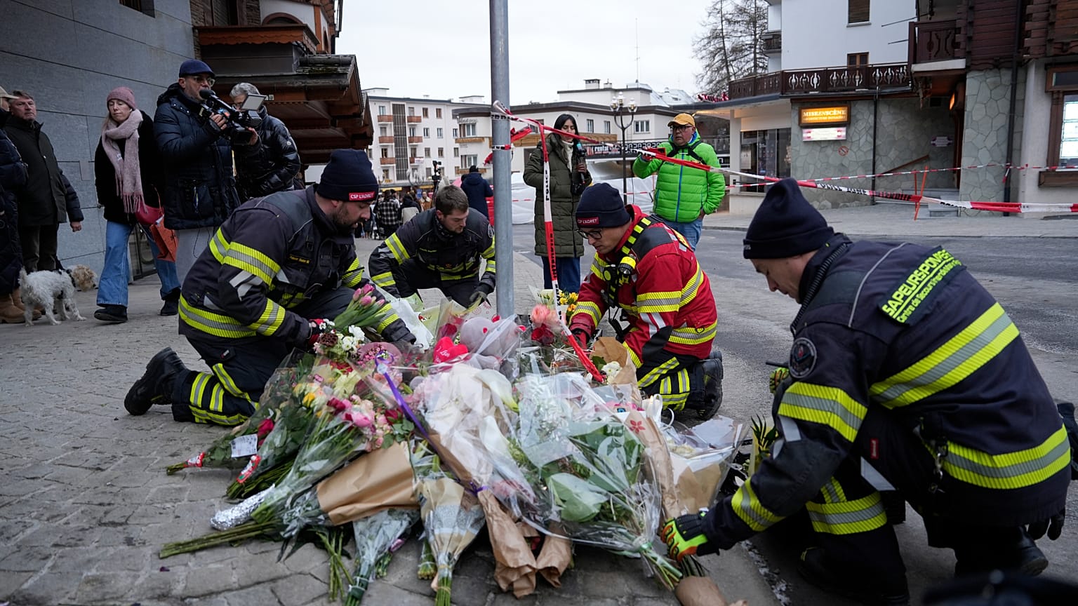 Firefighters lay flowers near the sealed off Le Constellation bar in Crans-Montana, Swiss Alps, Switzerland