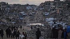 الفلسطينيون يسيرون بجانب مبانٍ مدمرة في شمال قطاع غزة، يوم الجمعة 2 يناير/كانون الثاني 2026.