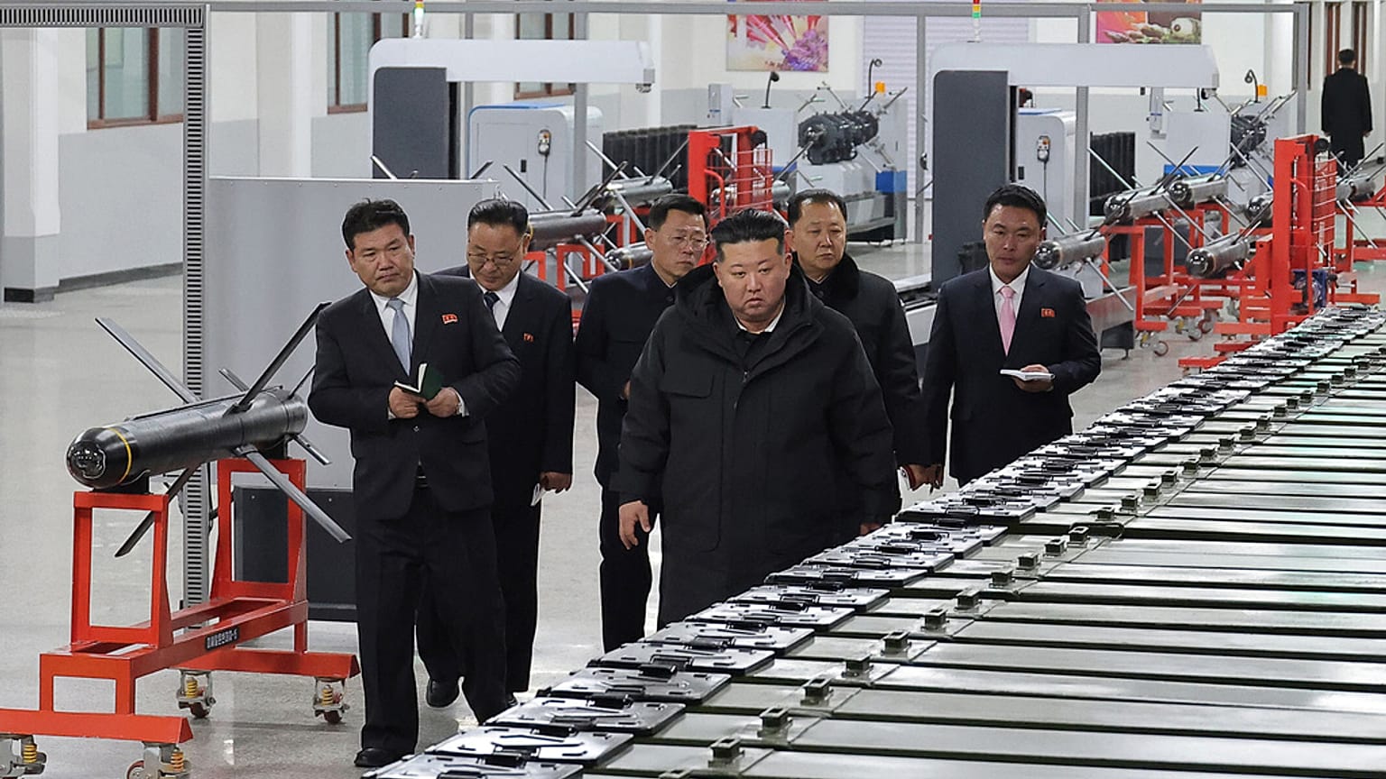 Az észak-koreai kormány által biztosított fotón Kim Dzsongun, az ország vezetője (jobbra elöl) egy ismeretlen helyen található nagy lőszergyárat látogat meg Észak-Koreában, s