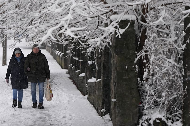 Des passants marchent dans une rue enneigée lors d'une chute de neige à Belgrade, en Serbie, le dimanche 4 janvier 2026