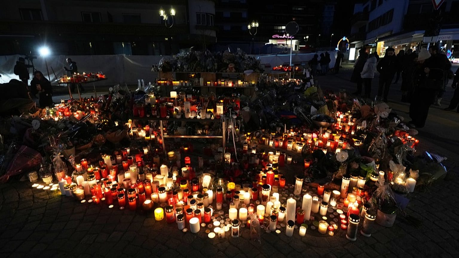 La gente enciende velas y coloca ofrendas florales fuera del bar sellado Le Constellation en Crans-Montana, Alpes suizos, Suiza, domingo 4 de enero de 2026.