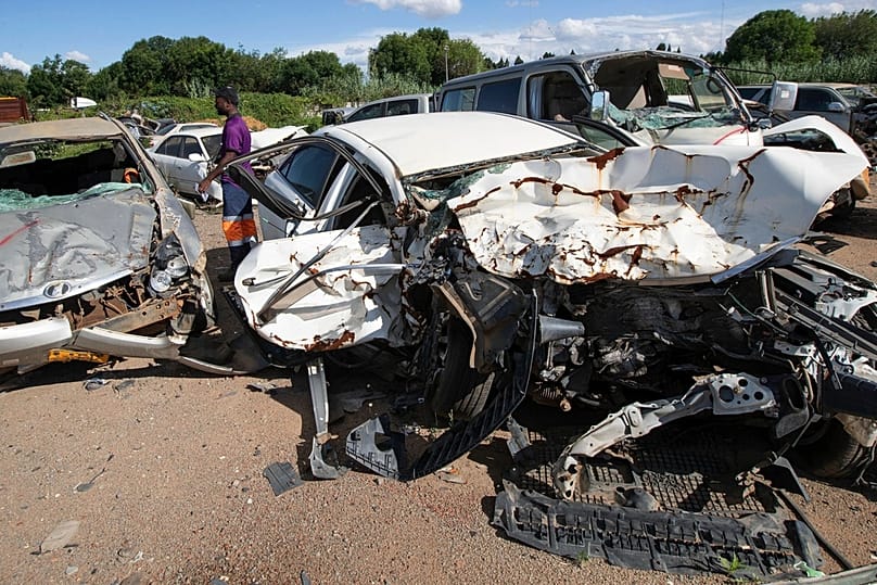 A worker at the vehicle inspection department checks on accident damaged vehicles in Harare, Zimbabwe, Tuesday, Dec. 16, 2025.