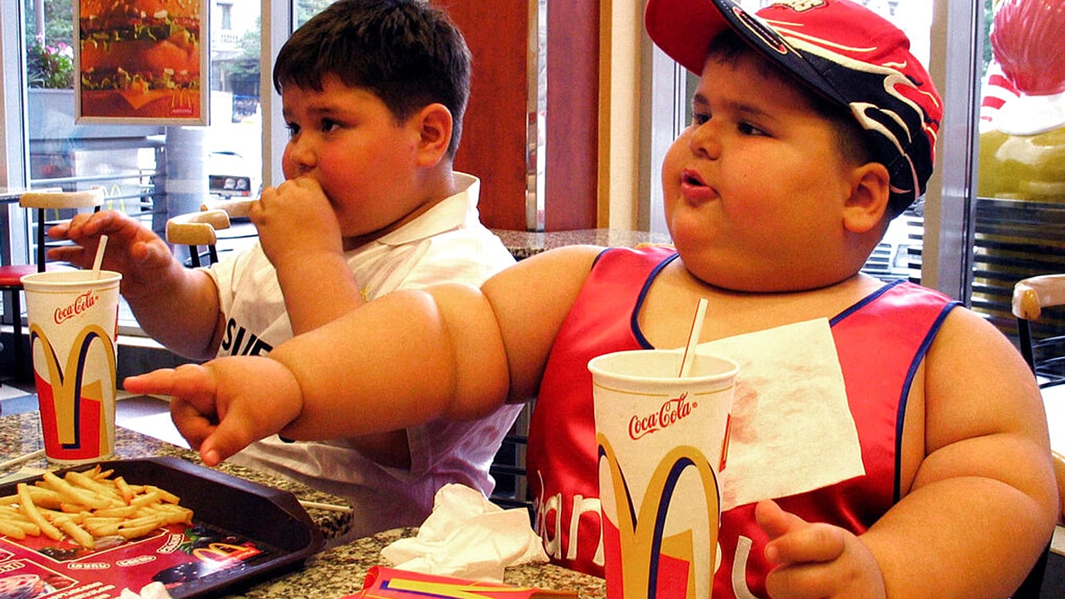 صورة تعبيرية لطفل يعاني من السمنة يتناول وجبات سريعة