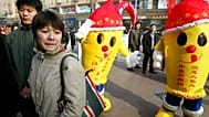 A couple walks past men dressed as condoms at an AIDS awareness activity held in Beijing Saturday, Nov. 29, 2003 ahead of World AIDS Day