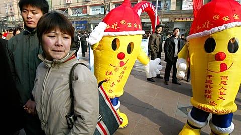 Un couple passe devant des hommes vêtus de préservatifs lors d'une activité de sensibilisation au sida organisée à Pékin le samedi 29 novembre 2003 à l'occasion de la Journée mondiale du sida.