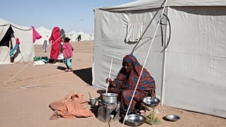 امرأة سودانية نازحة من الفاشر تطبخ خارج خيمتها في المخيم الجديد الأفاضل بمدينة الدبة بولاية شمال السودان، يوم الأحد 16 نوفمبر 2025.