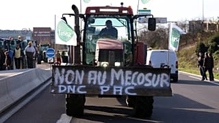 Un agricoltore francese guida il suo trattore per bloccare una strada principale durante una protesta contro l'accordo commerciale Mercosur con le nazioni sudamericane, dicembre 2025