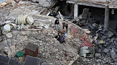 Pessoas procuram entre os escombros de um edifício destruído por um ataque aéreo israelita numa zona comercial da cidade portuária de Sidon, no sul