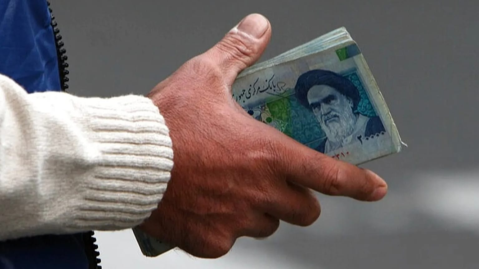 FILE - In this Thursday, Oct. 30, 2008 file photo, an Iranian money changer holds currency with Ayatollah Ruhollah Khomeini's image in Tehran, Iran.