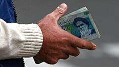 FILE - In this Thursday, Oct. 30, 2008 file photo, an Iranian money changer holds currency with Ayatollah Ruhollah Khomeini's image in Tehran, Iran.