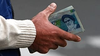 FILE - In this Thursday, Oct. 30, 2008 file photo, an Iranian money changer holds currency with Ayatollah Ruhollah Khomeini's image in Tehran, Iran.