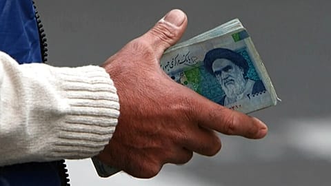 FILE - In this Thursday, Oct. 30, 2008 file photo, an Iranian money changer holds currency with Ayatollah Ruhollah Khomeini's image in Tehran, Iran.