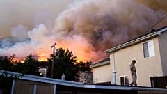 Chase Cho, à direita, e o filho Chris no telhado da casa, em La Crescenta, subúrbio de Los Angeles, com incêndio a lavrar nas colinas acima, segunda-feira, 31 de ago. de 2009