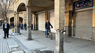 A man rides his bicycle as the others walk while shops are closed during protests in Tehran's centuries-old main bazaar, Iran, 6 January 2026
