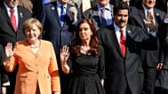 Angela Merkel and Nicolas Maduro waving at a political event.