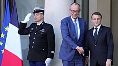 O Presidente francês Emmanuel Macron (à direita) dá as boas-vindas ao Chanceler alemão Friedrich Merz aquando da sua chegada a uma reunião da "Coligação de Vontades" sobre a Ucrânia.