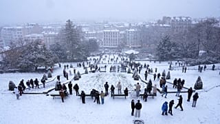 Pessoas descem a colina durante a queda de neve no bairro de Montmartre, segunda-feira, 5 de janeiro de 2026, em Paris