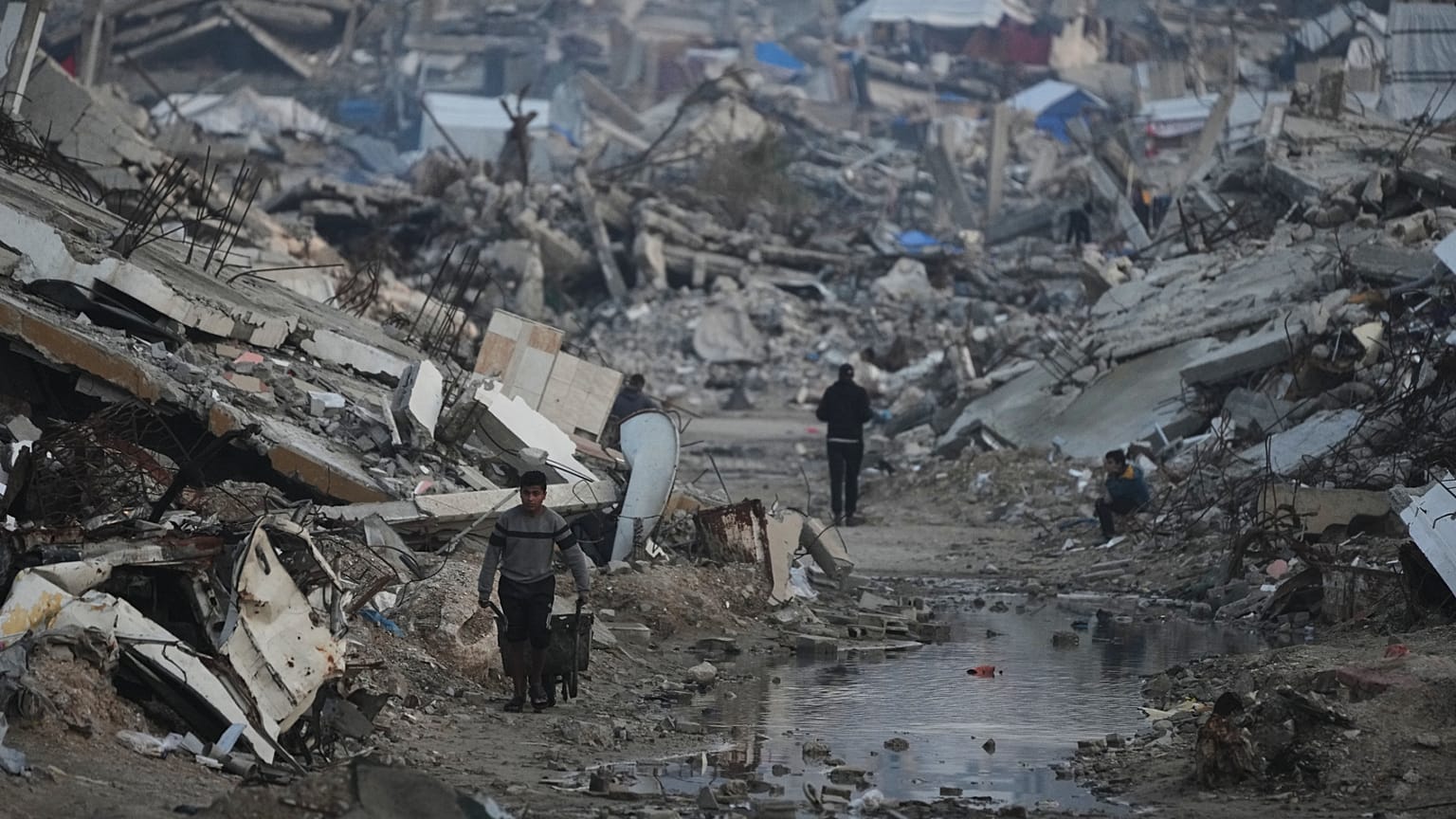 فلسطينيون يسيرون وسط مبانٍ دمّرتها الغارات الجوية والعمليات البرية الإسرائيلية في مدينة غزة، الثلاثاء 6 يناير/كانون الثاني 2026.