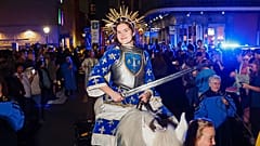 Eine als Jeanne d’Arc verkleidete Frau lächelt für ein Foto auf einem Pferd. Die jährliche Prozession zu Ehren Jeanne d’Arcs zieht durch das French Quarter in New Orleans.