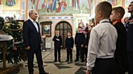 Russian President Vladimir Putin, second left, accompanied by military personnel and their families, attends an Orthodox Christmas service
