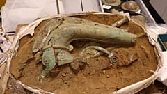 Nachdem die Schildbuckel und die Eberstandarte aus dem Block geborgen wurden, kommt die Carnyx, die Trompete, zum Vorschein.