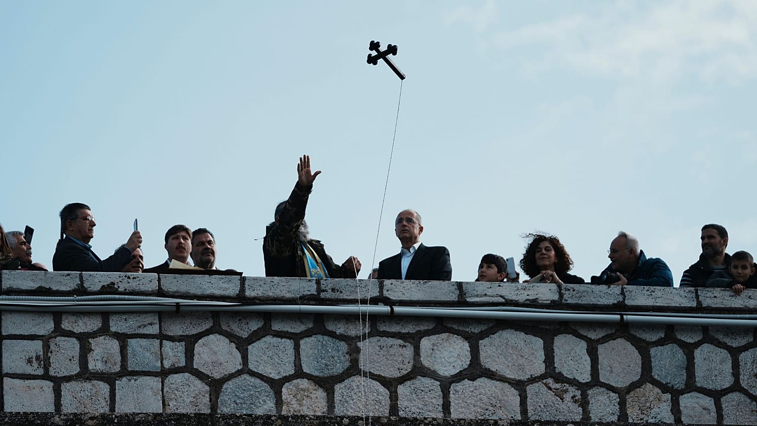 Atina yakınlarındaki Maraton Gölü'nde, bir Yunan Ortodoks papazı gölün çekilen sularını kutsamak için haç atarken insanlar Epifani ayinine katılıyor, 6 Ocak 2026.