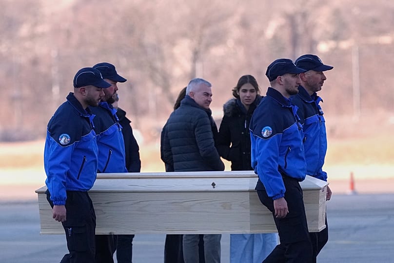 Police officers carry a coffin with the body of one of six Italians at the Military Airport in Sion, Swiss Alps, Switzerland, Monday, Jan. 5, 2026,following a devastating fire