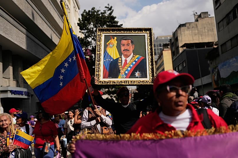 Une sympathisante du gouvernement porte une photo du président Nicolas Maduro lors d'une marche de femmes réclamant son retour à Caracas, le 6 janvier 2026.