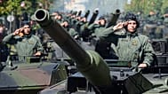 FILE - On 15 August 2017 in Warsaw, Poland, Polish Army tank troops salute as their tanks roll on one of the city's main streets during a yearly military parade.