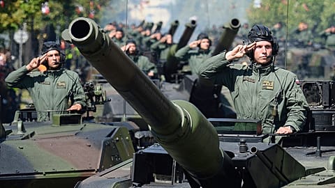FILE - On 15 August 2017 in Warsaw, Poland, Polish Army tank troops salute as their tanks roll on one of the city's main streets during a yearly military parade.