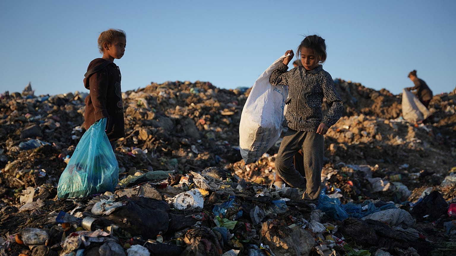 أطفال فلسطينيون يبحثون عن مواد قابلة لإعادة الاستخدام في مكب نفايات في دير البلح، وسط قطاع غزة، السبت 3 يناير 2026. 