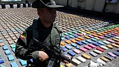 Un policía monta guardia sobre paquetes de cocaína incautada durante una presentación a los medios en el puerto pacífico de Buenaventura, 10 de agosto de 2017.