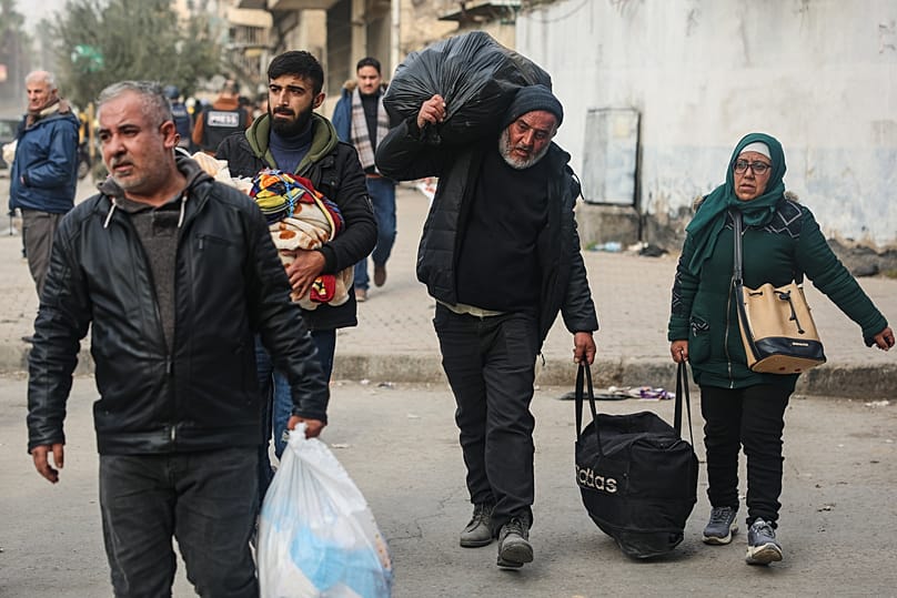 Residents carry their belongings as they are fleeing from Sheikh Maqsoud and Achrafieh neighbourhoods in Aleppo, 8 January, 2026
