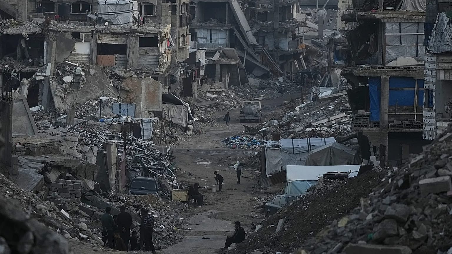 Filistinliler Gazze'de İsrail'in hava ve kara operasyonları sonucu yıkılan binaların arasında yürürken, 6 Ocak 2026