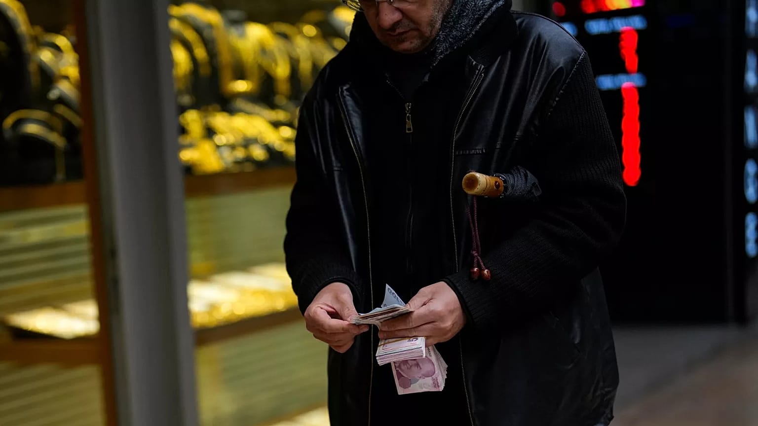 Son 6 aylık enflasyon verisiyle en düşük emekli maaşı 18 bin 938 TL'ye olmuştu. / İstanbul Eminönü'ndeki bir döviz bürosunun önünde para sayan bir adam / 25 Ocak 2024.