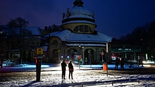 Passers-by stand in the light of a fire department help point in Berlin, Germany, Saturday, Jan. 3, 2025, during a power cut in south-west Berlin after a fire on a bridge.