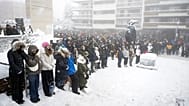 People observe a minute of silence as they watch the official commemorative ceremony on a screen in Martigny, 9 January, 2026