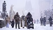 People cross the medieval Charles Bridge during a heavy snowfall in Prague, 9 January, 2026