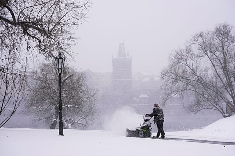 A man clears snow from a walking path during a heavy snowfall in Prague, 9 January, 2026
