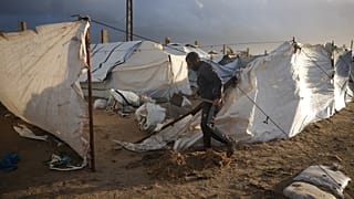 فلسطيني يعيد تدعيم خيمته بعد أن تضررت بسبب الطقس العاصف في مخيم خيام بدير البلح وسط قطاع غزة، يوم الجمعة 9 يناير 2026.