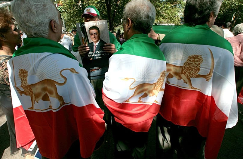 Iranian-American protesters drape themselves in pre-revolutionary imperial Iranian flags and carry pictures of their proclaimed "crown prince" Reza Pahlavi.