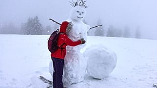 Frau umarmt einen Schneemann am Feldberg im Taunus